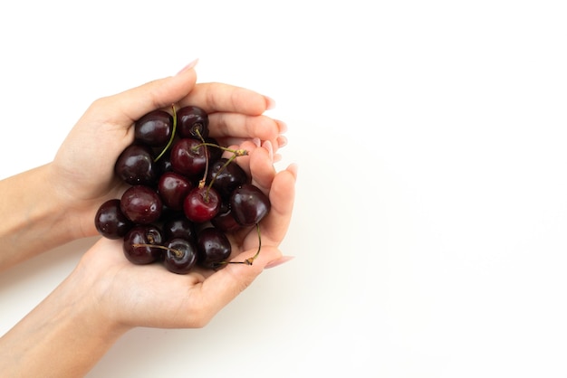 Una vista superior femenina sosteniendo cerezas en blanco, color de la fruta verano humano