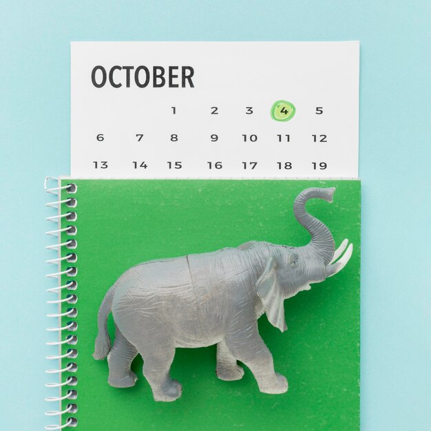 Vista superior de la figura de elefante con cuaderno y calendario para el día de los animales