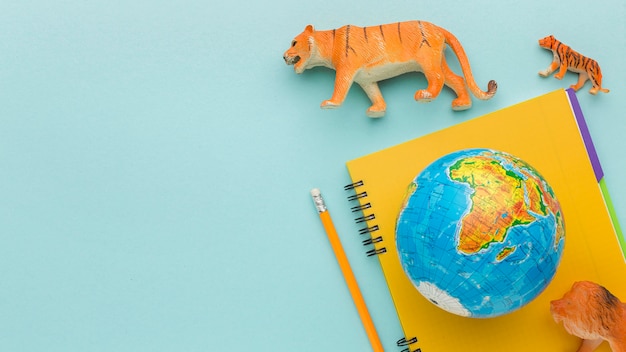 Vista superior de figuras de animales con cuaderno y planeta tierra para el día de los animales