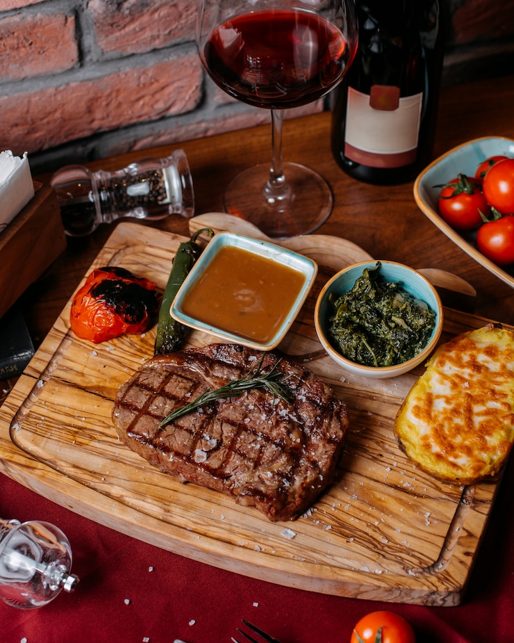 Foto gratuito vista superior de filete de res a la parrilla con papas desnudas y salsa sobre una tabla de madera