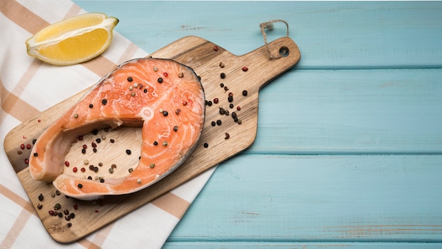 Foto gratuita vista superior de filete de salmón sobre tabla de madera con espacio de copia