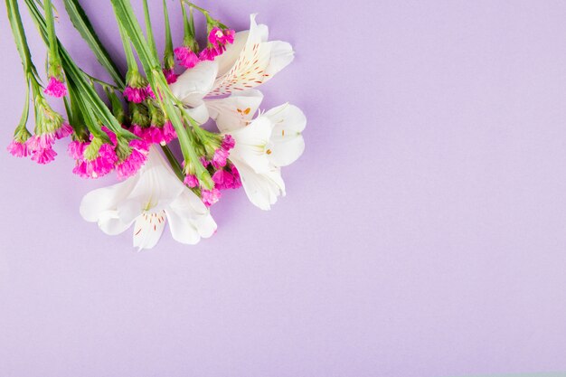 Vista superior de flores de alstroemeria y statice de color blanco y rosa sobre fondo lila con espacio de copia