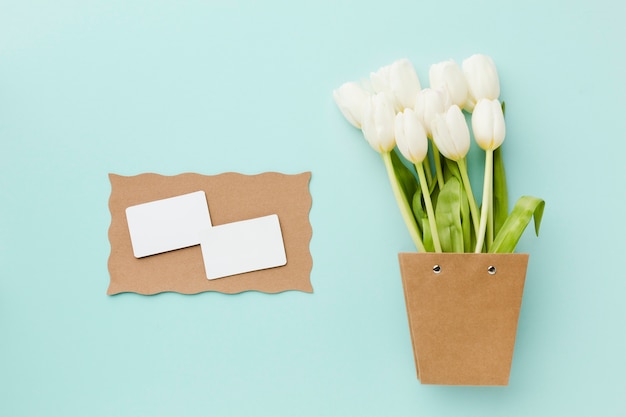 Vista superior de flores blancas de tulipán y tarjetas blancas vacías