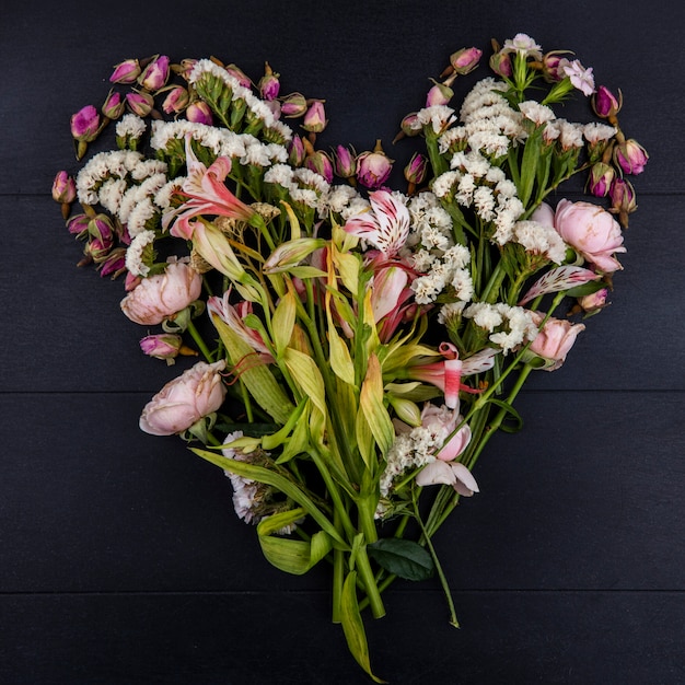 Foto gratuita vista superior de flores de color rosa claro en forma de corazón sobre una superficie negra