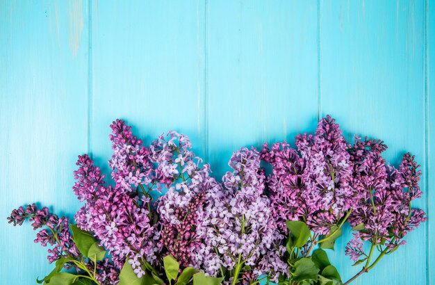 Vista superior de flores lilas aisladas sobre fondo de madera azul con espacio de copia