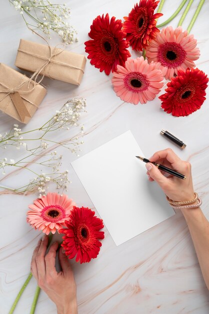 Vista superior de flores con tarjeta en blanco y regalos