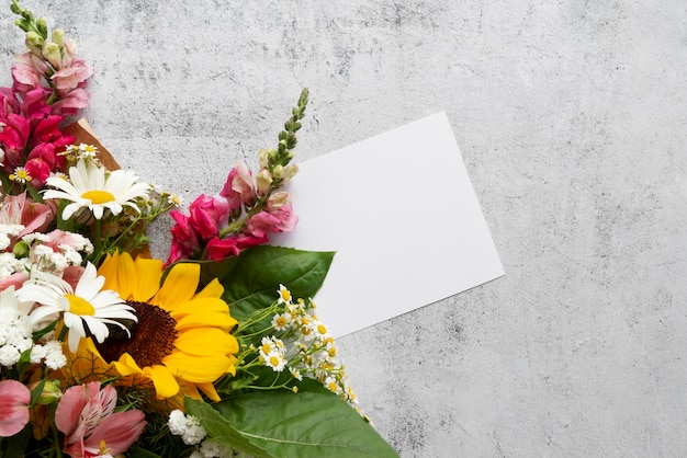 Vista superior de flores con tarjeta en blanco