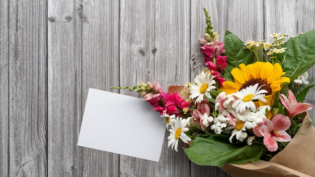 Foto gratuita vista superior de flores con tarjeta en blanco