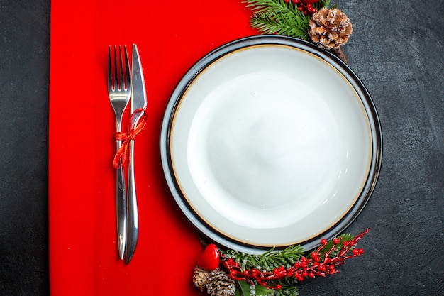 Vista superior del fondo de Navidad con accesorios de decoración de plato de cena, ramas de abeto y cubiertos en una servilleta roja