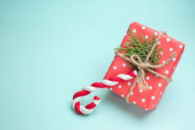 Vista superior del fondo de Navidad con caja de regalo roja y dulces sobre fondo verde pastel