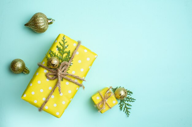 Vista superior del fondo de Navidad con cajas de regalo amarillas en diferentes tamaños y accesorios de decoración sobre fondo verde pastel