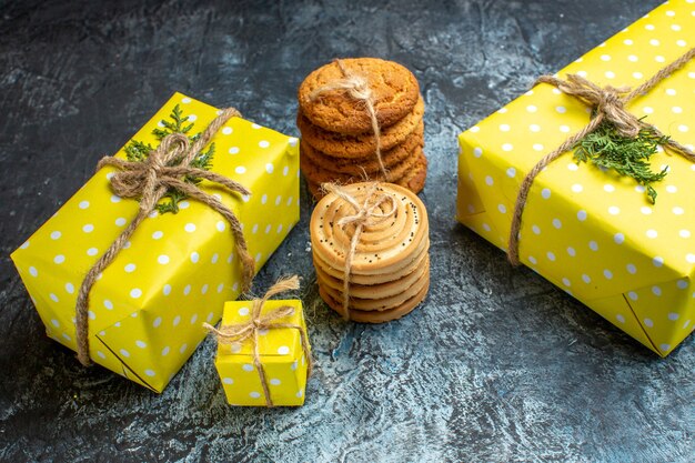 Vista superior del fondo de Navidad con hermosas cajas de regalo amarillas y galletas apiladas en la mesa oscura