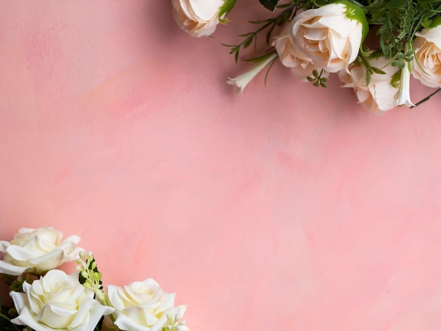 Vista superior de fondo rosa con marco de rosas blancas