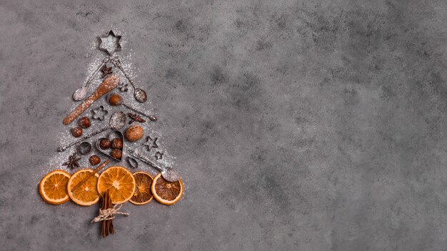 Vista superior de la forma del árbol de navidad hecha de cítricos secos y utensilios de cocina