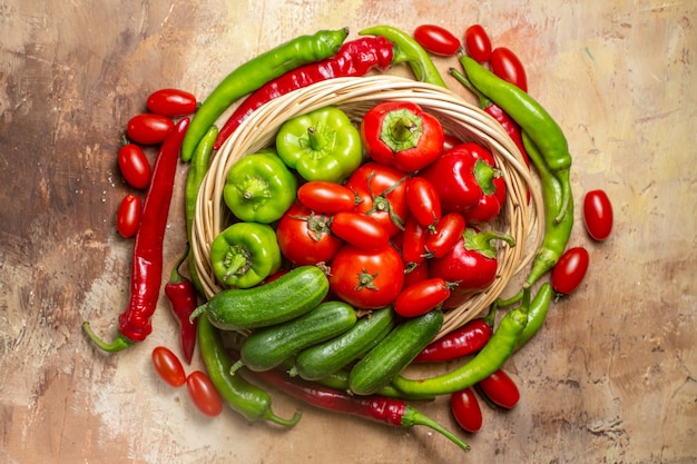 Vista superior forma de círculo pimientos picantes y tomates cherry una canasta de verduras en un círculo sobre la superficie de color ámbar