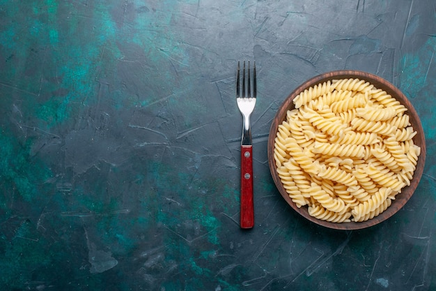 Vista superior en forma de pasta italiana deliciosa pasta poco en el escritorio azul oscuro