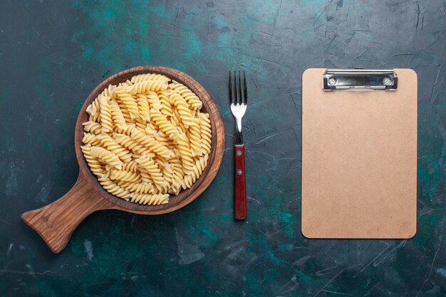 Vista superior en forma de pasta italiana deliciosa pasta poco en el escritorio azul oscuro