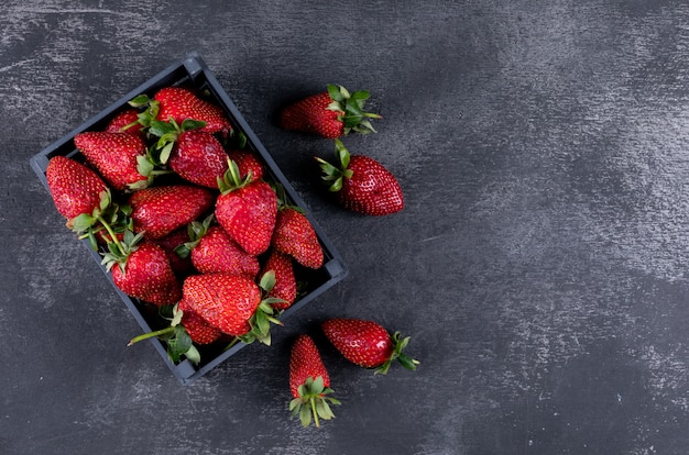 Vista superior de fresas en una caja y otras alrededor