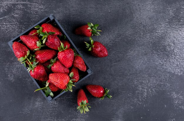 Vista superior de fresas en una caja y otras alrededor