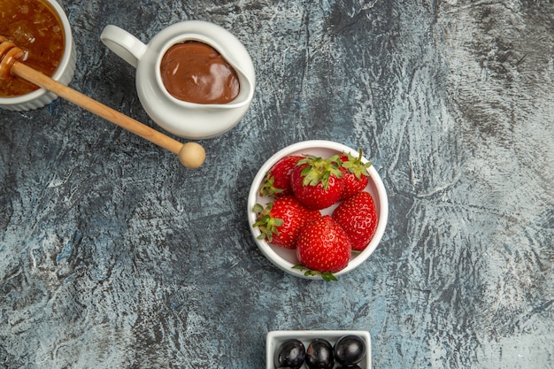 Foto gratuita vista superior de fresas frescas con aceitunas y miel en la superficie oscura de la baya de fruta dulce