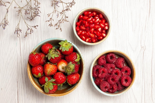 Vista superior de fresas frescas con frambuesas y granadas en el escritorio blanco Berry fruta fresca suave madura salvaje