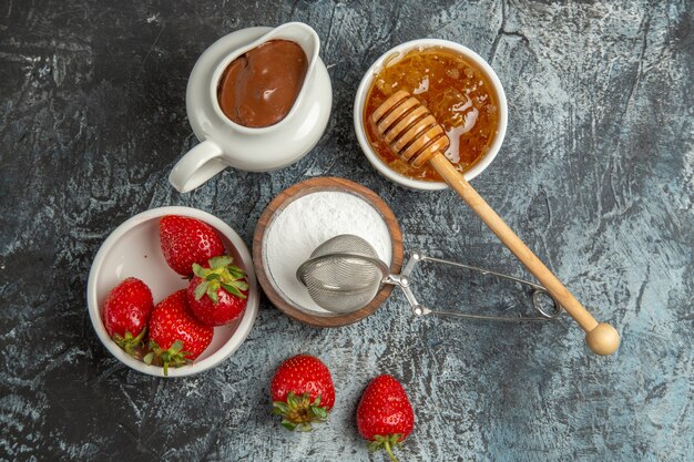 Vista superior de fresas frescas con miel en la superficie oscura dulce de bayas de frutas