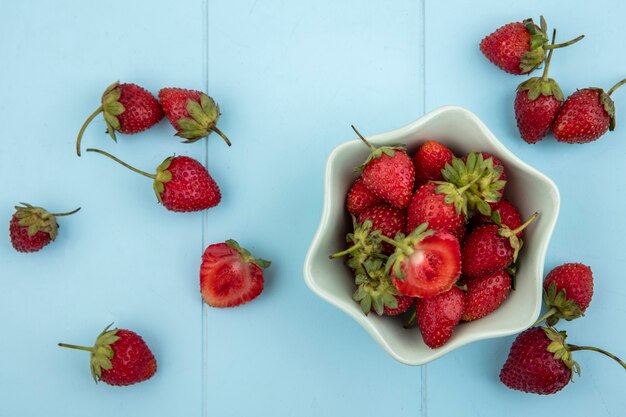 Vista superior de fresas frescas en un recipiente con fresas aislado sobre un fondo azul.