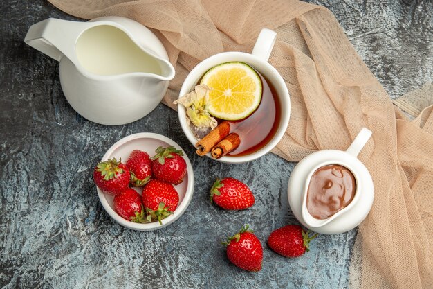 Vista superior de fresas frescas con taza de té en bayas de frutos rojos de superficie oscura-clara