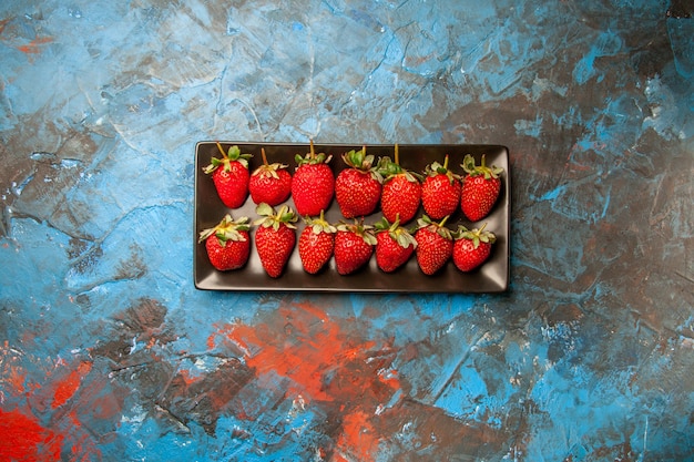 Foto gratuita vista superior de fresas rojas dentro de una sartén negra sobre fondo azul.