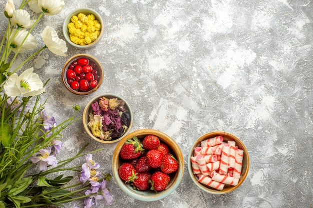 Vista superior de fresas rojas frescas con caramelos en la superficie blanca de la fruta de baya de caramelo fresco