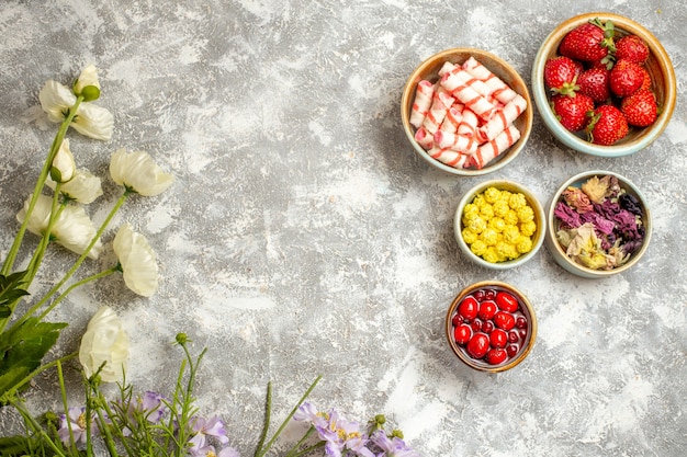 Foto gratuita vista superior de fresas rojas frescas con caramelos en la superficie blanca de la fruta de caramelo de baya