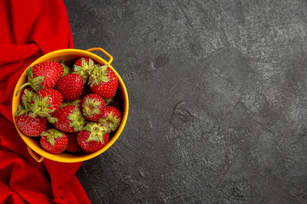 Vista superior de fresas rojas frescas dentro de la canasta en la baya de fruta de mesa oscura