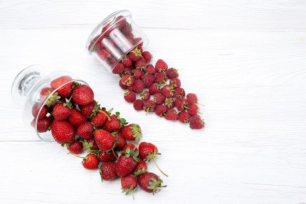 Vista superior de fresas rojas frescas dentro y fuera de la placa en luz blanca, fruta baya fresca suave