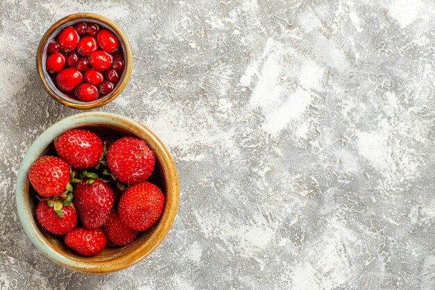 Vista superior de fresas rojas frescas dentro de una pequeña olla en la superficie blanca de frutos rojos de frutas