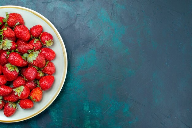 Vista superior fresas rojas frescas frutas melosas bayas dentro de la placa sobre el fondo azul oscuro baya verano suave