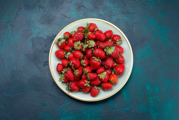 Vista superior fresas rojas frescas frutas melosas bayas dentro de la placa sobre el fondo azul oscuro baya verano suave