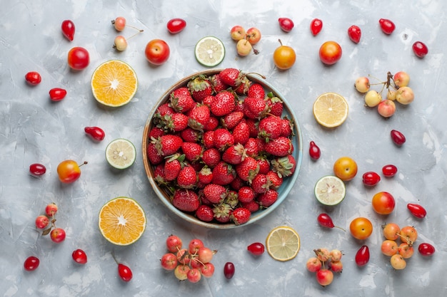 Vista superior de fresas rojas frescas con limón y cerezas en el escritorio blanco, fruta, baya, vitamina, suave