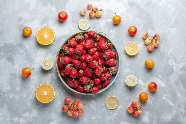 Vista superior de fresas rojas frescas con limón y cerezas en el escritorio blanco fruta baya vitamina verano suave