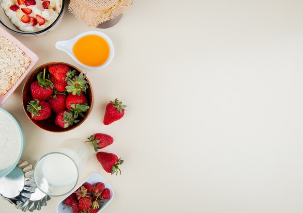 Vista superior de fresas en un tazón con requesón mantequilla mantequilla avena en el lado izquierdo y blanco con espacio de copia