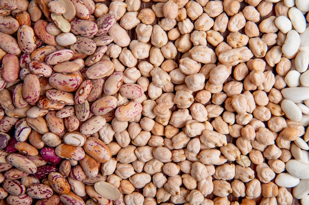 Vista superior de frijoles blancos y coloridos con guisantes en una superficie de madera marrón