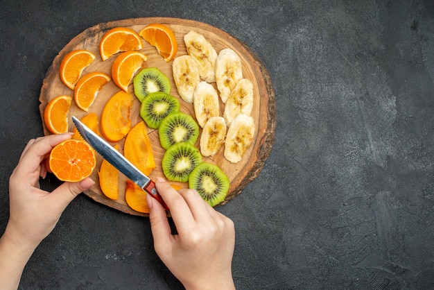 Vista superior de la fruta fresca orgánica natural en la tabla de cortar en el lado derecho sobre fondo oscuro