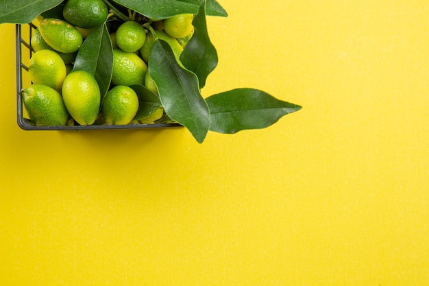 Vista superior de frutas cítricas cesta de frutas cítricas verdes con hojas