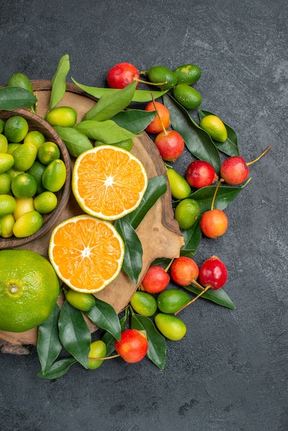 Vista superior de frutas cítricas de frutas lejanas con hojas en el tablero y cerezas