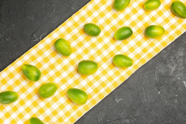 Foto gratuita vista superior de frutas cítricas en el mantel a cuadros en la mesa oscura