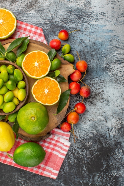 Vista superior de frutas cítricas manzanas frutas cítricas en el tablero en las cerezas mantel a cuadros