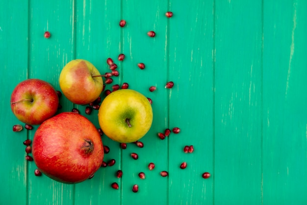 Foto gratuita vista superior de frutas como granada y manzana en superficie verde con espacio de copia