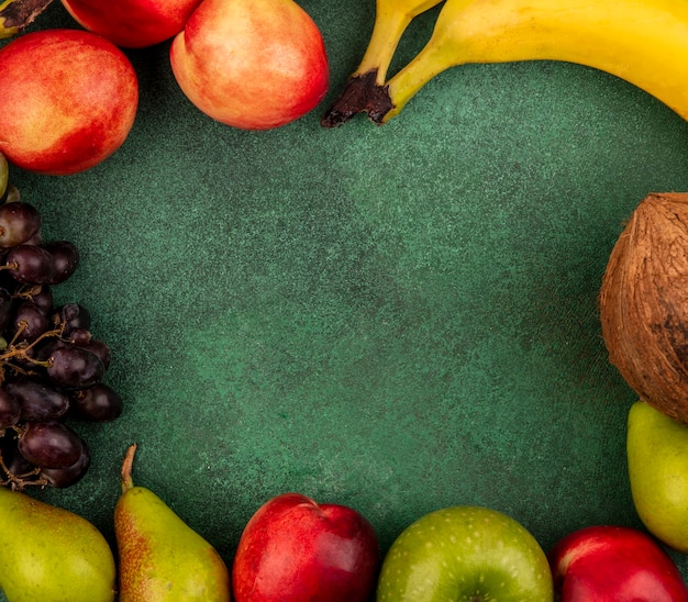 Vista superior de frutas como melocotón coco manzana pera plátano uva sobre fondo verde con espacio de copia