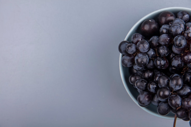Foto gratuito vista superior de frutas como uva y endrinas en un recipiente sobre fondo gris con espacio de copia