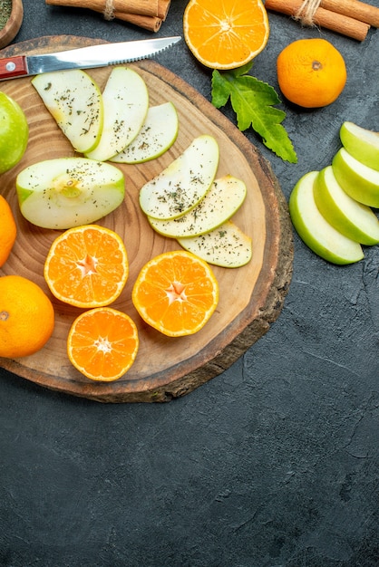 Vista superior de frutas cortadas en tablero de madera sobre fondo oscuro