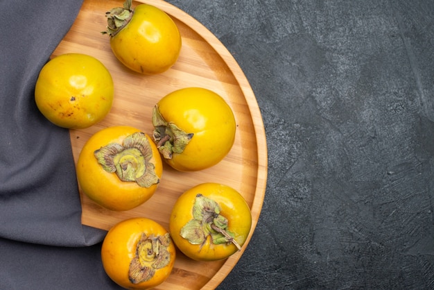 Foto gratuita vista superior de frutas dulces maduras de caqui fresco en la mesa oscura fruta madura suave